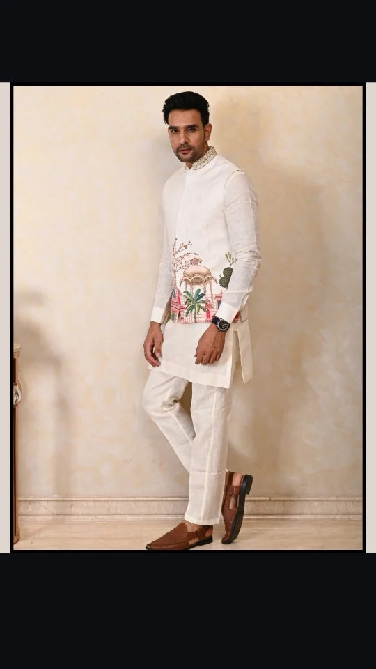 Step into royalty with this ivory Nehru jacket — a wearable work of art. Inspired by miniature paintings, the hand-embroidered palace, domes, and trees bring timeless elegance to life. Crafted in a linen-silk blend for the perfect drape, this piece speaks tradition with a modern twist.

#RoyalElegance #HandEmbroidered #NehruJacket #MensEthnicWear #IvoryJacket #MiniatureArt #LinenSilk #EthnicFashion #TimelessStyle #LuxuryMenswear